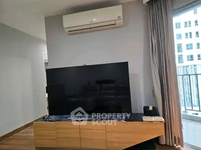 Modern living room with large TV and balcony view, featuring sleek air conditioning unit.