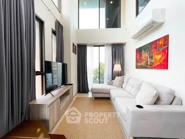 Modern living room with high ceilings, large windows, and stylish decor in a contemporary apartment.