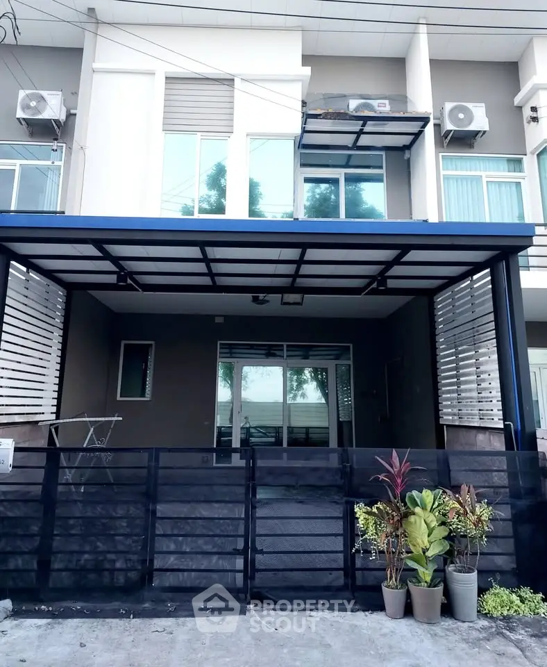 Modern townhouse exterior with gated entrance and potted plants