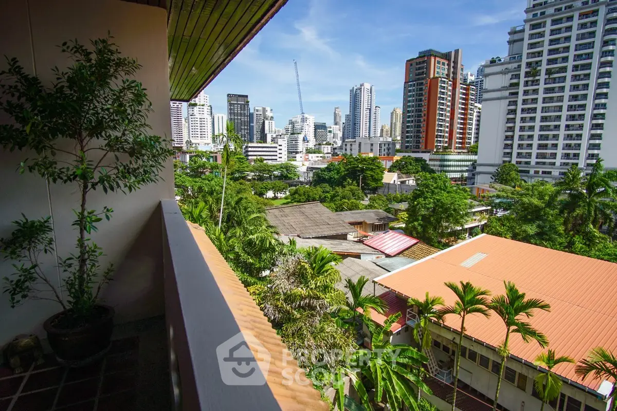 Stunning cityscape view from a balcony overlooking lush greenery and modern skyscrapers.