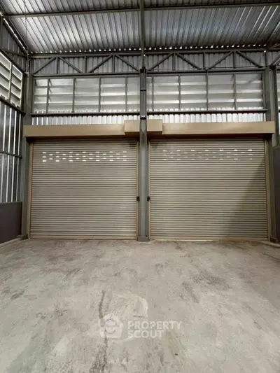 Spacious industrial garage with dual roller doors and high ceilings, perfect for storage or workshop use.