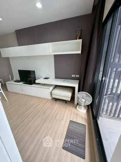 Modern living room with sleek white furniture and balcony access, featuring a minimalist design and ample natural light.