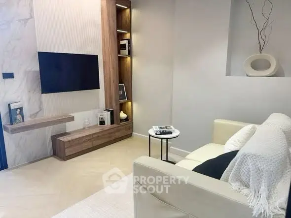 Modern living room with sleek TV setup and cozy sofa in stylish apartment.