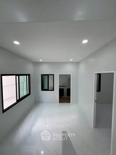 Spacious modern living room with sleek white interiors and large windows for natural light.