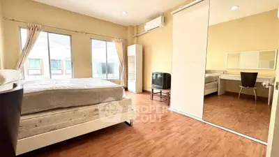 Spacious bedroom with wooden flooring, large window, and mirrored wardrobe in modern apartment.