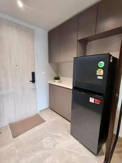 Modern kitchen corner with sleek fridge and ample storage cabinets.