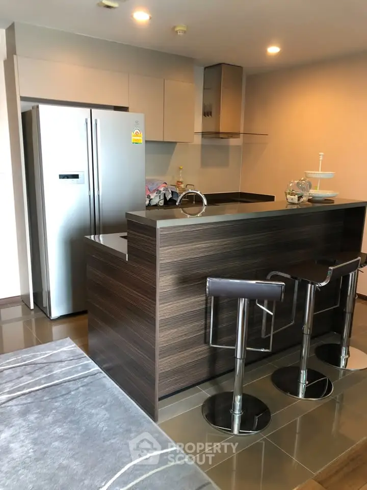 Modern kitchen with sleek design, featuring a breakfast bar and stainless steel appliances.