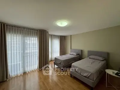 Spacious bedroom with twin beds and large windows for natural light.