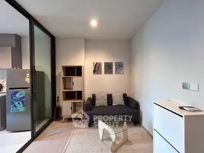 Modern living room with stylish furniture and glass partition, featuring a cozy sofa and contemporary decor.