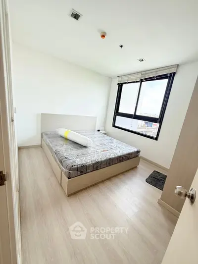 Bright bedroom with modern decor and city view window.