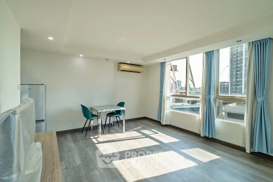 Bright and airy living room with large windows and modern furnishings in a high-rise apartment.