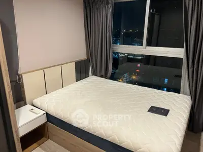 Modern bedroom with large window offering city night view, featuring a comfortable bed and stylish decor.