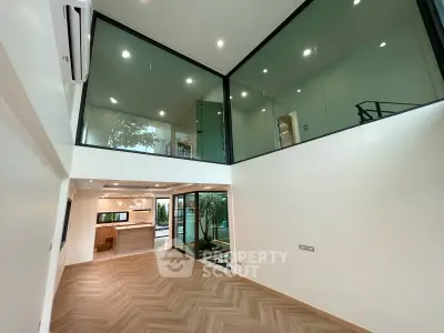 Stunning modern living room with high ceilings and glass walls, featuring elegant wood flooring and open layout.