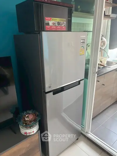 Modern kitchen with sleek stainless steel refrigerator and microwave, featuring stylish cabinetry and glass sliding door.