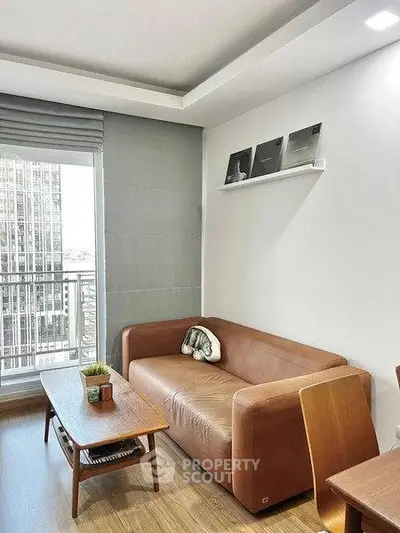Modern living room with leather sofa and city view balcony in a stylish apartment.