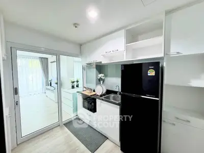 Modern kitchen with sleek appliances and open layout leading to bright living area.