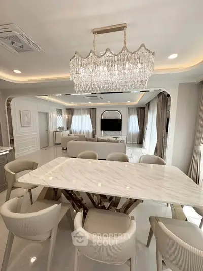 Luxurious open-plan living and dining area with elegant chandelier and marble table.