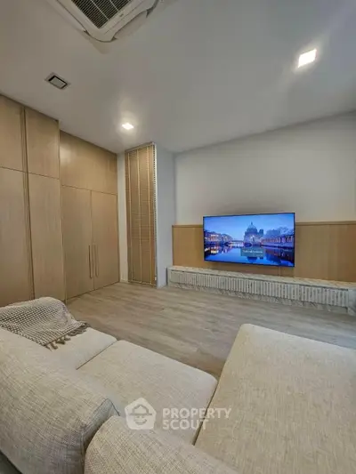 Spacious modern living room with sleek wooden cabinetry and large flat-screen TV, perfect for relaxation.