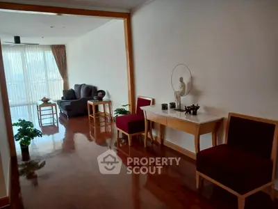 Elegant living room with polished wooden floors and stylish furniture, featuring a cozy seating area and decorative accents.