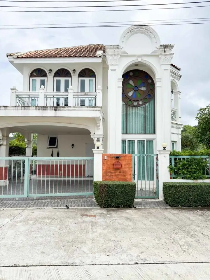 Elegant two-story house with arched windows and gated entrance, featuring a unique circular stained glass window.