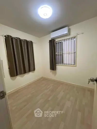 Cozy unfurnished bedroom with wooden flooring and air conditioning, perfect for customization.
