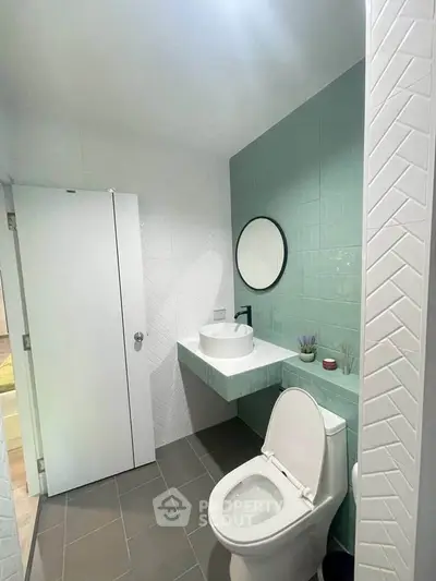 Modern bathroom with sleek design, featuring a round mirror and stylish basin.
