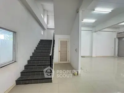 Spacious commercial space with tiled flooring and staircase, ideal for business setup.