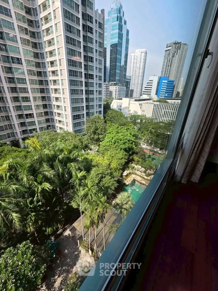 Stunning cityscape view from high-rise apartment window overlooking lush greenery and modern skyscrapers.