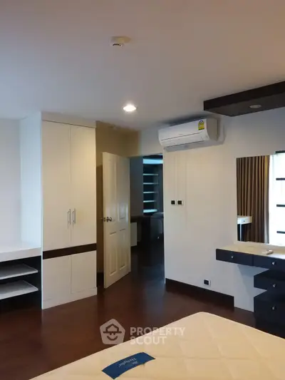 Spacious bedroom with modern furnishings and built-in air conditioning unit.