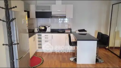 Modern kitchen with sleek white cabinets and breakfast bar in cozy apartment.