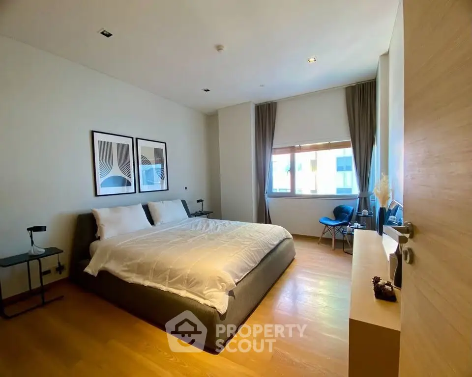 Spacious modern bedroom with large window and stylish decor in luxury apartment.