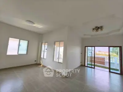 Spacious living room with large windows and balcony access, perfect for natural light lovers.