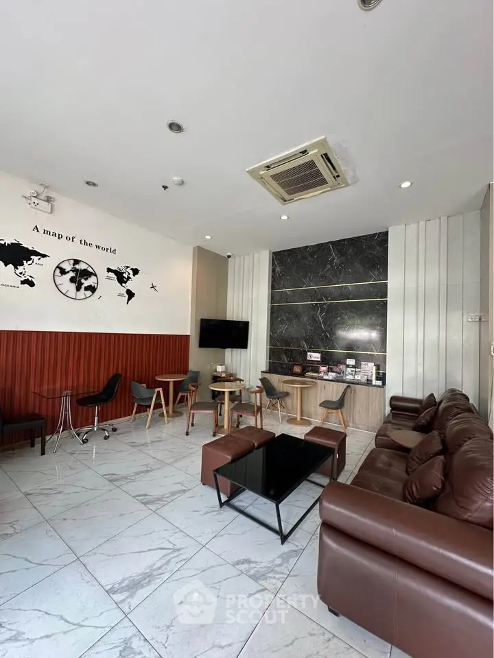 Modern lounge area with leather sofas, wall map decor, and sleek marble accents.