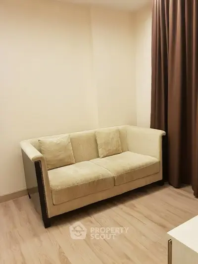 Cozy living room with beige sofa and wooden flooring, perfect for relaxation.