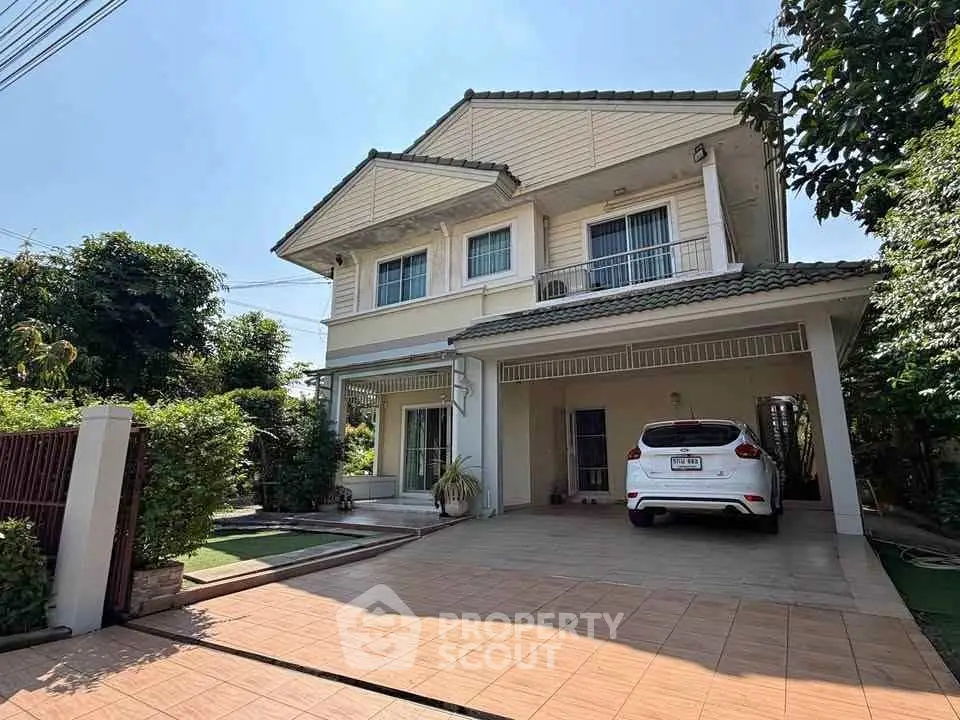 Charming two-story house with spacious driveway and lush greenery, perfect for family living.