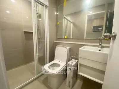 Modern bathroom with sleek fixtures and glass shower enclosure in a contemporary apartment.