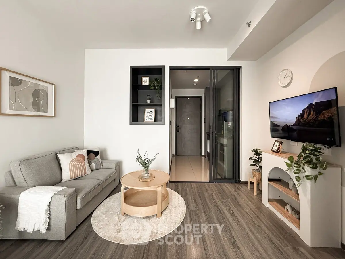 Modern living room with stylish decor and wall-mounted TV, featuring cozy seating and elegant flooring.