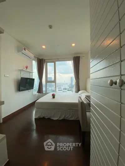 Modern bedroom with city view, featuring large windows and sleek design.