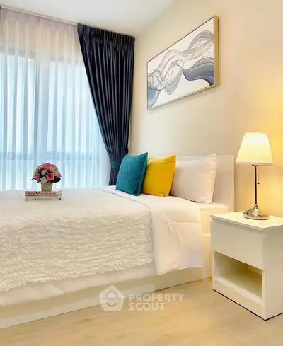 Elegant bedroom with modern decor, cozy bedding, and natural light through sheer curtains.