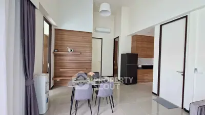 Modern dining area with sleek furniture and stylish kitchen in open layout apartment.