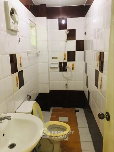 Compact bathroom with tiled walls and basic fixtures, featuring a shower and toilet.