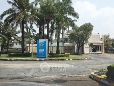 Charming residential neighborhood entrance with palm trees and directional signs.