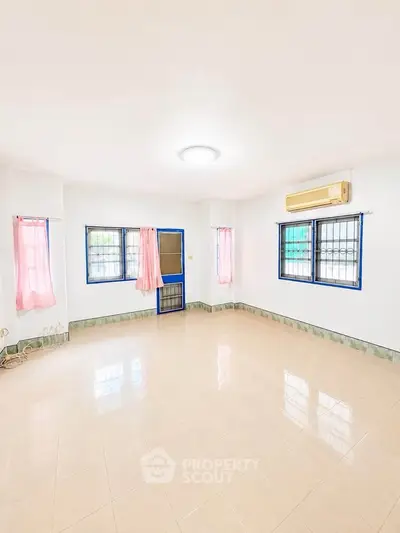 Spacious and bright living room with tiled flooring and large windows, perfect for family gatherings.