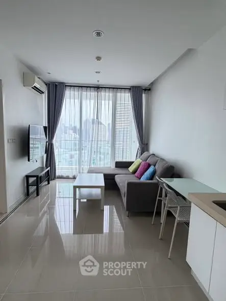Modern living room with city view, featuring sleek furniture and large windows for natural light.