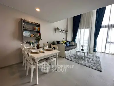Modern living room with dining area, featuring elegant decor and large windows for natural light.