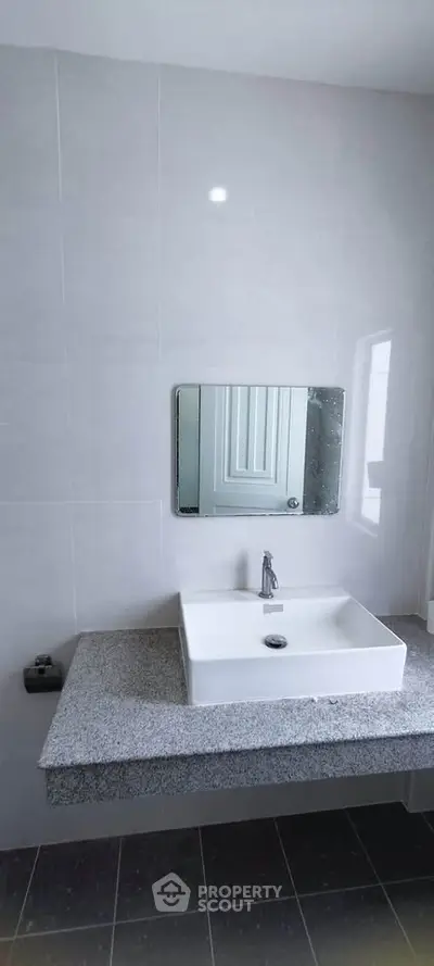 Modern bathroom with sleek sink and mirror, featuring minimalist design and neutral tones.