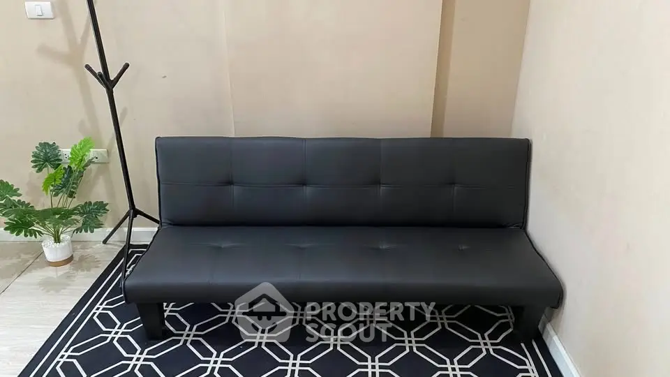 Modern black sofa in a cozy living room with stylish decor and indoor plant.