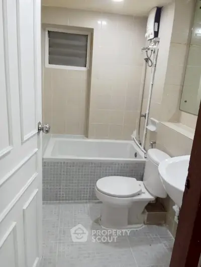 Modern bathroom with bathtub and shower in a sleek tiled design.