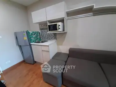 Compact studio apartment with kitchenette and cozy seating area, ideal for urban living.