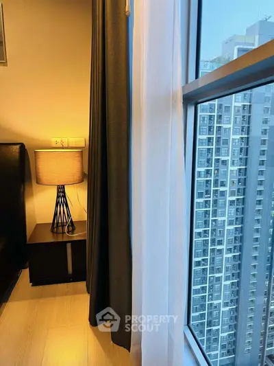 Modern bedroom with city view, stylish lamp, and floor-to-ceiling window for natural light.